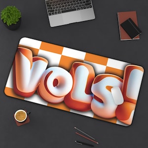 May include: Orange and white chequered mouse mat with the word "VOLS!" in a 3D, cartoon-style font.