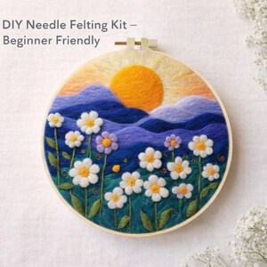 May include: A needle felting kit with a landscape design. The artwork features a bright yellow sun, blue mountains, and white daisies with yellow centers. The text "DIY Needle Felting Kit - Beginner Friendly" is at the top.