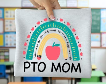 May include: A light grey t-shirt with a colourful design featuring a rainbow, apple, and the text "PTO MOM". The rainbow is teal, yellow, and pink, with arrows and hearts. The apple is red with a green leaf.