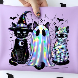 May include: A light purple pouch featuring a graphic of three cats: one wearing a witch hat, one dressed as a ghost, and one wrapped like a mummy. The design includes a spiderweb background, bats, and the text The Clippy Arts Co. in a circle.