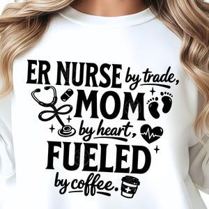 May include: White sweatshirt featuring the text "ER NURSE by trade, MOM by heart, FUELED by coffee." The design includes a stethoscope, pill, baby footprints, a heart with a heartbeat line, and a coffee cup.
