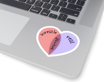 May include: A heart-shaped sticker with a Venn diagram inside. The left side of the heart is pink and says "wrestle". The right side of the heart is purple and says "rest". The overlapping section is white and says "believe".
