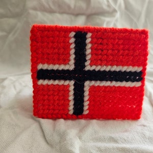 May include: A red, white, and black crocheted flag with a cross design.