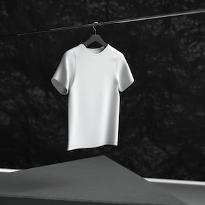 May include: A white t-shirt hanging on a black hanger against a dark background.