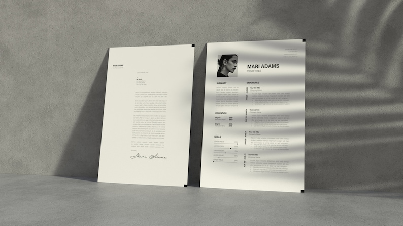 May include: Two off-white paper documents lean against a gray wall. The document on the right is a resume with a photo of a person and the name "Mari Adams". The document on the left is a letter. Both have black text.