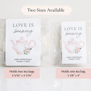 May include: Two clear plastic pouches containing tea bags with white labels. The labels feature a pink teapot illustration, floral accents, and the text 'LOVE IS brewing', 'Ashlan's Bridal Shower', and 'October 17, 2028'. Sizes are 4 5/16" x 4 5/16" and 3 3/8" x 4".