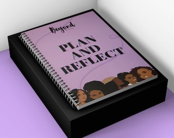 Pode incluir: Um caderno espiralado com uma capa lavanda com o texto "PLAN AND REFLECT" e o logotipo "Beyond Black". A capa também exibe ilustrações de rostos de mulheres diversas. O caderno repousa sobre uma caixa preta.