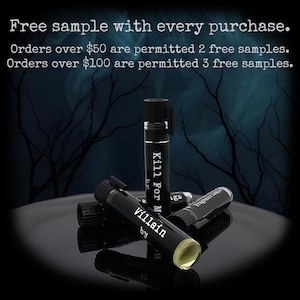 May include: Small black fragrance sample vials with black caps. The labels feature white text reading 'Villain by' and 'Kill For Me'. The vials are arranged in a cluster, with one standing upright and others lying horizontally, revealing a pale yellow liquid.
