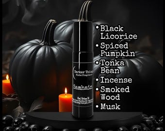 May include: A black cylindrical perfume oil bottle labeled Darker Things Niche Fragrances Samhain 10ml. The label lists scent notes: Black Licorice, Spiced Pumpkin, Tonka Bean, Incense, Smoked Wood, and Musk. The bottle is centered against a dark background.