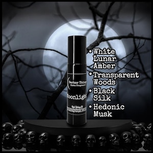 May include: A black perfume bottle with a black cap, labeled "Moonlight" with scent notes listed: White Lunar Amber, Transparent Woods, Black Silk, and Hedonic Musk. The background features a full moon and tree branches.