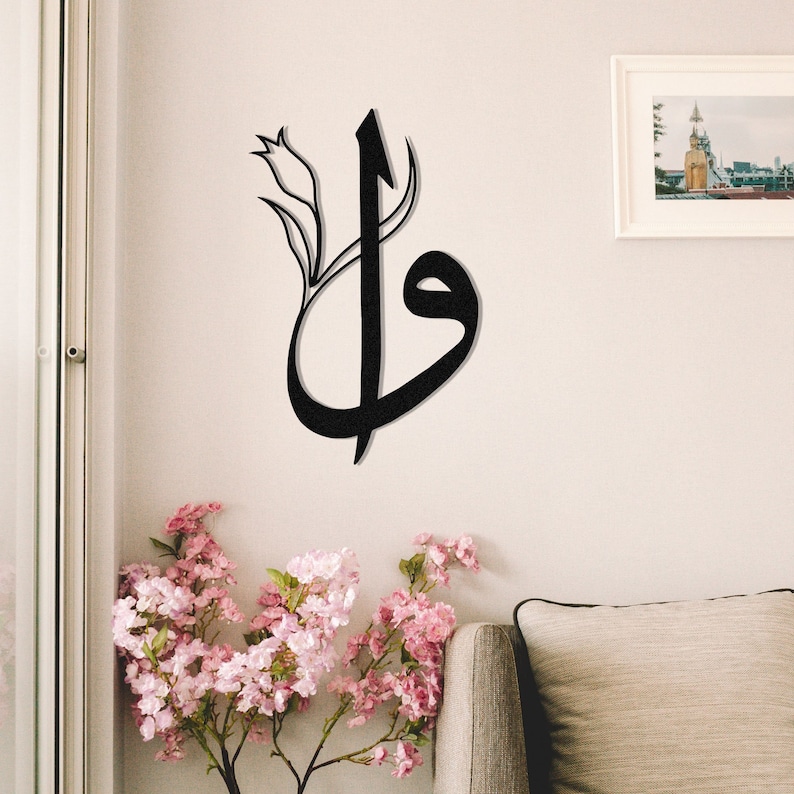 May include: Black metal wall art featuring Arabic calligraphy with a floral accent. The artwork is mounted on a light-colored wall, creating a striking contrast. The design incorporates a stylized tulip, adding a touch of elegance.