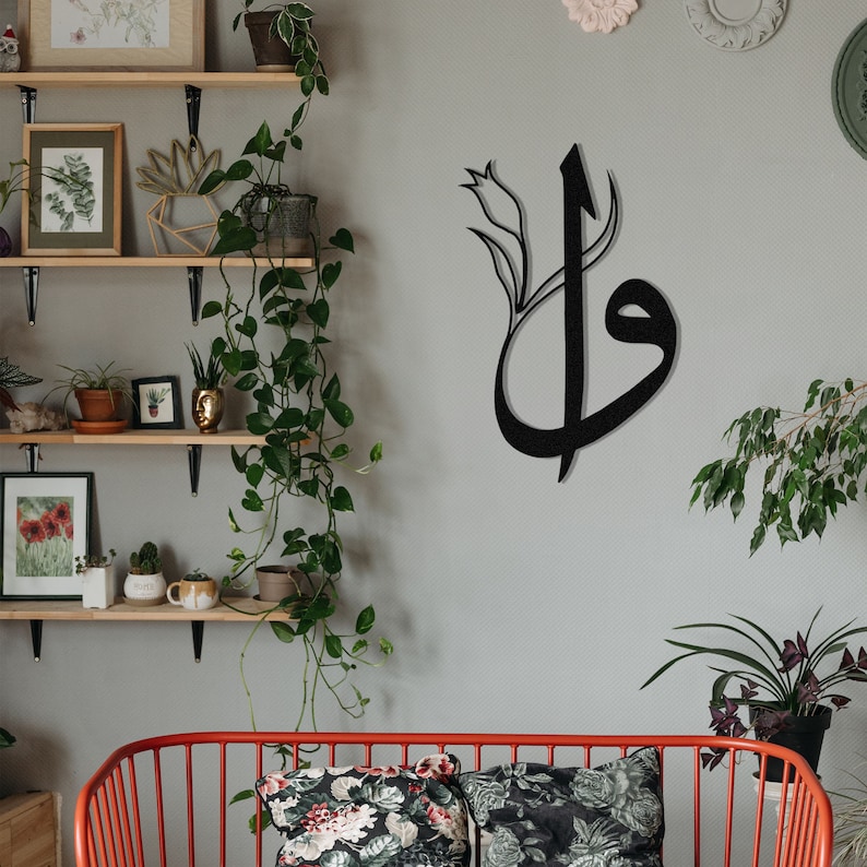 May include: Black metal wall art featuring stylized Arabic calligraphy with a floral accent. The artwork is mounted on a light gray wall, creating a striking contrast. The design adds a touch of elegance and cultural flair to any interior space.