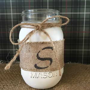 May include: White mason jar with a burlap ribbon and the letter "S" in black. The jar is sitting on a burlap surface.