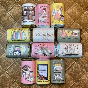 Könnte beinhalten: Ein Set mit 10 bunten Geschenkanhängern zum Thema Bücher mit verschiedenen Designs und Sprüchen. Die Anhänger zeigen Illustrationen von Büchern, Kaffeetassen und anderen buchbezogenen Gegenständen. Einige der Sprüche lauten: "Ich mag meine Bücher würzig", "Erweitere deinen Horizont", "In meiner Buch-Ära", "Frieden Liebe Buch", "Nur noch ein Kapitel", "Wenn ich sterbe, lösche meinen Kindle-Verlauf", und "Lesen ist meine Therapie".