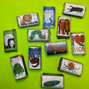 May include: A collection of ten wrapped book-themed favors featuring Eric Carle's children's books. The favors include titles such as "The Very Hungry Caterpillar", "The Very Busy Spider", "The Very Lonely Firefly", "The Foolish Tortoise", "Brown Bear, Brown Bear, What Do You See?", "Polar Bear, Polar Bear, What Do You Hear?", "To the Zoo", "The Very Chasey Chick Beetle", and "I Love Mom".