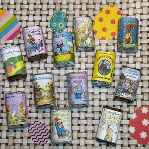 May include: A collection of 14 colorful wrapped chocolate bars with different children's book covers featuring characters like Curious George, Paddington Bear, and Peter Rabbit. The covers are decorated with Easter themes and include titles like "Happy Easter Mouse!" and "It's Easter Little Critter!"