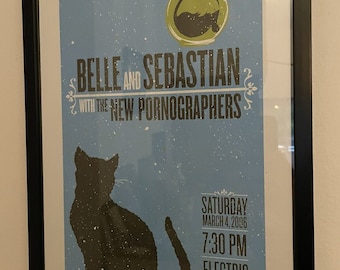 May include: A concert poster for Belle and Sebastian with the New Pornographers. The poster features a black cat silhouette and a fishbowl with a fish inside. The concert is on Saturday, March 4, 2006 at 7:30 PM at the Electric Factory.