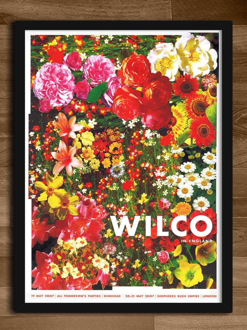 May include: A concert poster for Wilco, a band, performing in England. The poster features a colorful floral design with red, pink, yellow, and white flowers. The text "Wilco in England" is printed in white on a black background. The dates and locations of the concerts are listed at the bottom of the poster: "19 May 2007 All Tomorrow's Parties Minehead 20-21 May 2007 Shepherds Bush Empire London."