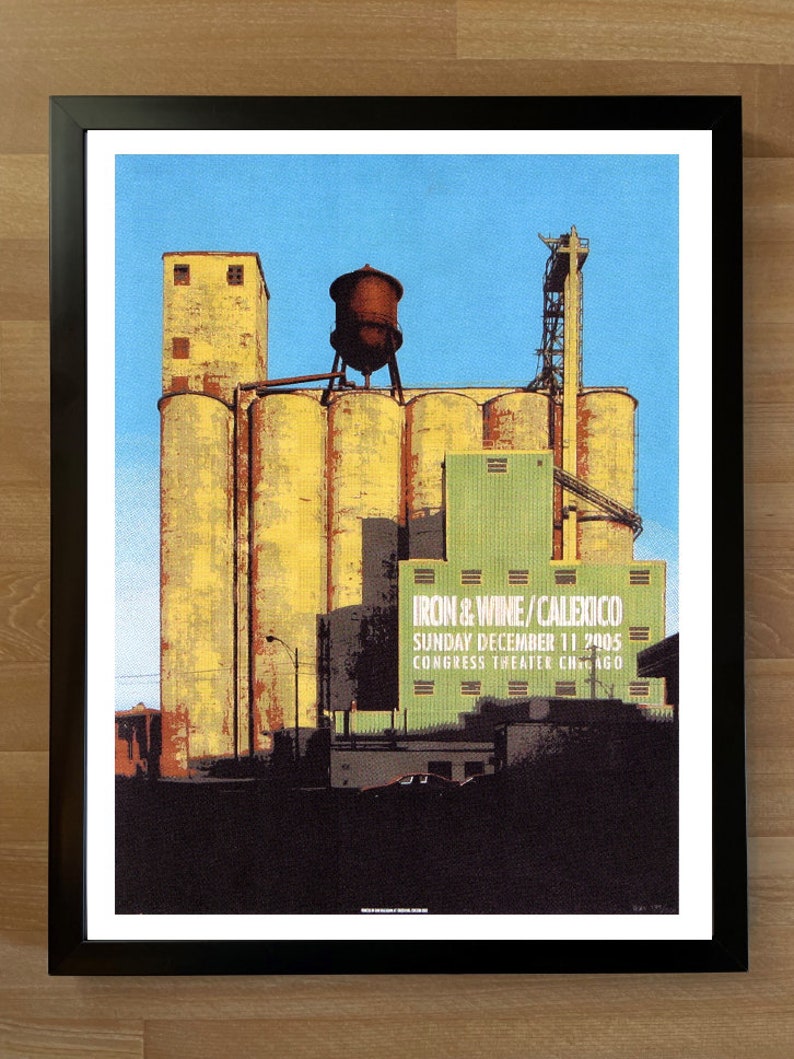 May include: A vintage concert poster advertising a show featuring Iron & Wine and Calexico. The poster features a graphic of a large industrial building with silos and a water tower. The text on the poster reads "Iron & Wine/Calexico Sunday December 11 2005 Congress Theater Chicago"
