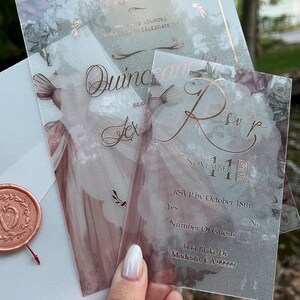 May include: A clear, floral-patterned RSVP card with rose gold lettering. The card includes the date "November 11, 2023", RSVP instructions, and a space for the number of guests. The address is "4444 Blake Dr Modesto, CA 99999".