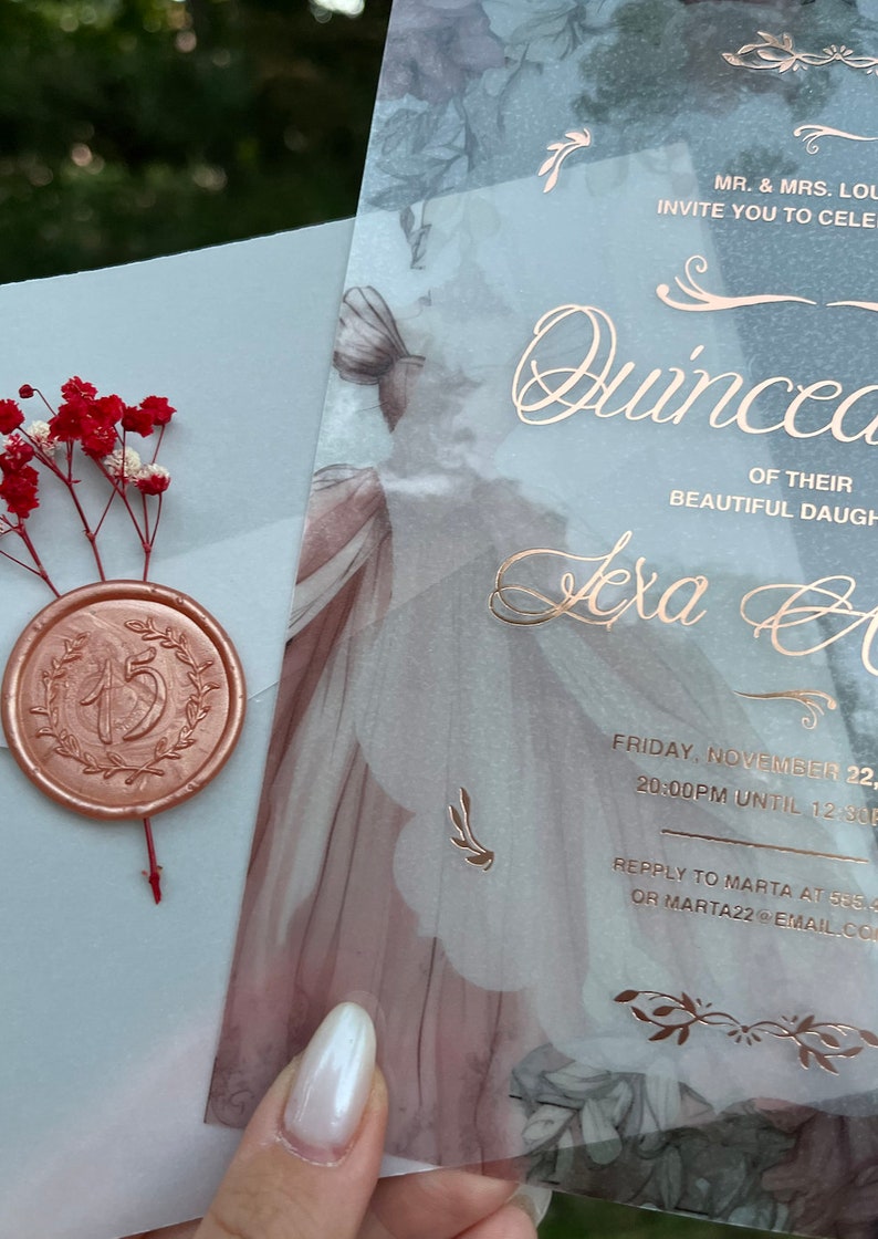 May include: A translucent blue and white invitation with gold lettering for a Quincea&ntilde;era. The invitation features a floral design and the text "MR. & MRS. LOU INVITE YOU TO CELEBRATE THE QUINCEA&Ntilde;ERA OF THEIR BEAUTIFUL DAUGHTER TEXA A FRIDAY, NOVEMBER 22, 20:00PM UNTIL 12:30 REPPLY TO MARTA AT 555 OR MARTA22@EMAIL.COM".