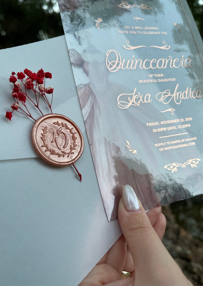 May include: A light blue invitation with gold lettering for a Quincea&ntilde;era celebration. The invitation features the name "Lexa Andrea" and the date "Friday, November 22, 2029".