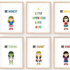 May include: Six framed art prints with inspirational messages and superhero illustrations. The prints feature phrases like "BE HONEST," "BE BRAVE," and "BE KIND." Each print has a white background with colorful text and cartoon superhero characters.