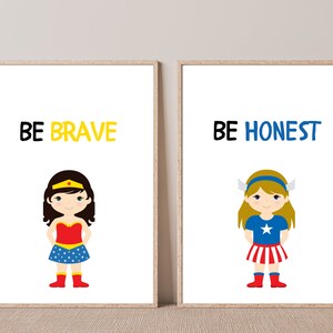 May include: Two framed art prints with cartoon illustrations of superhero girls. One print says "BE BRAVE" above a girl in a red and blue outfit. The other says "BE HONEST" above a girl in a blue and red outfit.