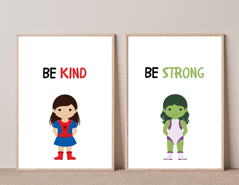 May include: Two framed art prints with cartoon illustrations. One print says "BE KIND" above a girl in a blue dress and red boots. The other says "BE STRONG" above a green-skinned character in a white and purple outfit.