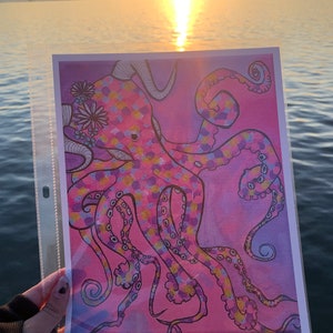 May include: A pink and purple octopus with yellow accents is drawn on a white background. The octopus has a crown of flowers on its head and is surrounded by a pink and purple watercolor background.