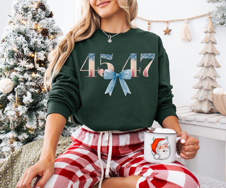 May include: A green sweatshirt with the numbers 45 47 printed in white with a red, white, and blue American flag design. A blue bow is centered between the numbers.