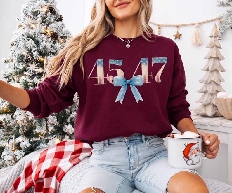 May include: A maroon sweatshirt with the number 4547 printed in white with a red, white, and blue design. A blue bow is centered below the number.