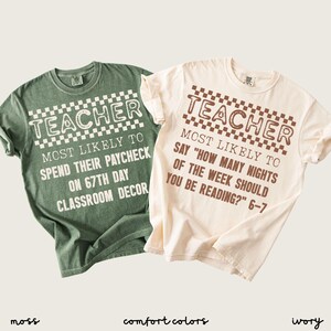 May include: Two t-shirts, one moss green and one ivory, with the word "TEACHER" in a checkered font. The green shirt says "MOST LIKELY TO SPEND THEIR PAYCHECK ON 67TH DAY CLASSROOM DECOR." The ivory shirt says "MOST LIKELY TO SAY 'HOW MANY NIGHTS OF THE WEEK SHOULD YOU BE READING?' 6-7."