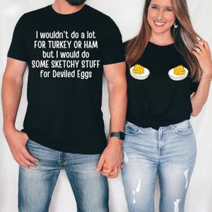 May include: Black t-shirts with humorous text and graphic designs. One shirt reads "I wouldn't do a lot FOR TURKEY OR HAM but I would do SOME SKETCHY STUFF for Deviled Eggs." The other shirt features devilled egg graphics.
