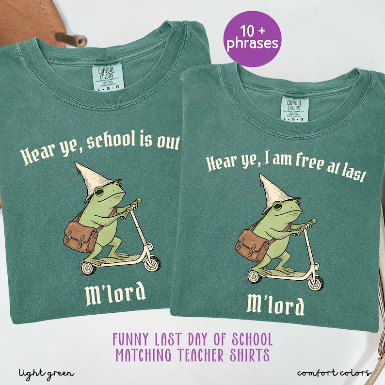 May include: Two light green Comfort Colors t-shirts. Each shirt features a cartoon frog riding a scooter, wearing a wizard hat and carrying a satchel. Text on the shirts reads "Hear ye, school is out" and "Hear ye, I am free at last".