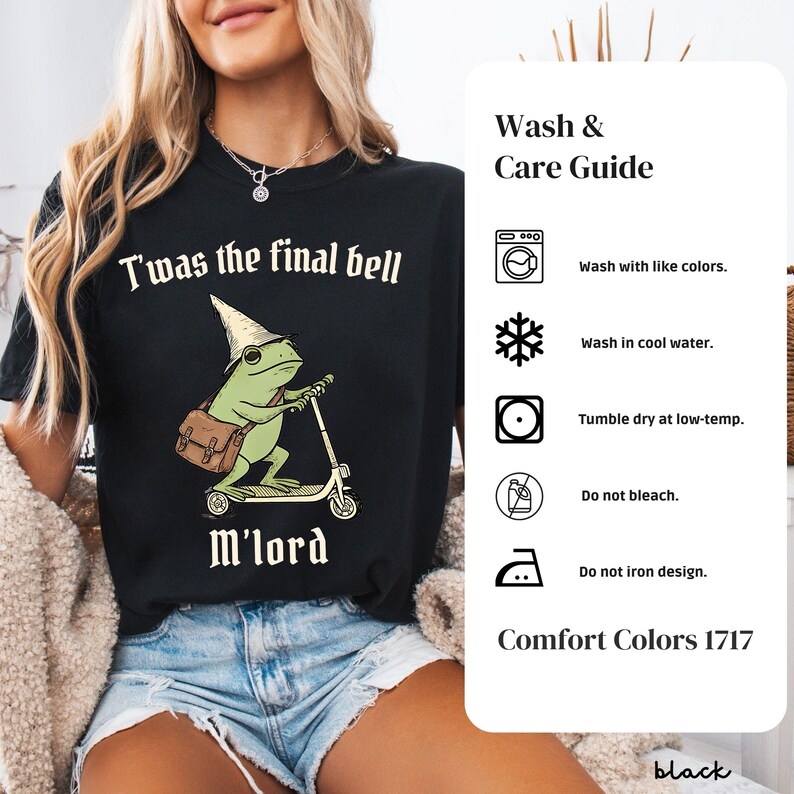 May include: Black t-shirt with the text "T'was the final bell M'lord" above a cartoon frog riding a scooter. The frog wears a wizard hat and carries a satchel. A wash and care guide is on the right.