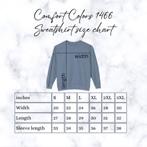 May include: A blue sweatshirt with a size chart. The chart shows measurements in inches for width, length, and sleeve length, ranging from S to 3XL. The text "Comfort Colors 1466 Sweatshirt size chart" is at the top.