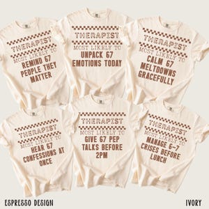 May include: Ivory-colored t-shirts with the word "THERAPIST" and various phrases like "MOST LIKELY TO UNPACK 67 EMOTIONS TODAY" in brown text. The shirts have a checkered design above the word "THERAPIST". The brand name "ESPRESSO DESIGN" is at the bottom.