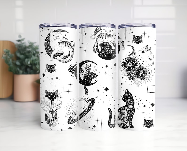 Pode incluir: Tr&ecirc;s copos de a&ccedil;o inoxid&aacute;vel com fundo branco e ilustra&ccedil;&otilde;es em preto e branco de gatos, luas e estrelas.