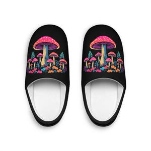 Puede incluir: Un par de pantuflas negras con un diseño de setas de colores. Las setas son de color rosa, naranja, amarillo y azul con tallos blancos. Las pantuflas tienen un forro blanco.