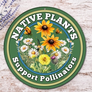 May include: A round, green metal sign with the words "NATIVE PLANTS" and "Support Pollinators" in white. The sign features a watercolor illustration of yellow and orange flowers and white daisies. A sprig of lavender is in the background.