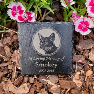 May include: Black slate stone memorial with a cat silhouette and the text "In Loving Memory of Smokey 2007-2013".