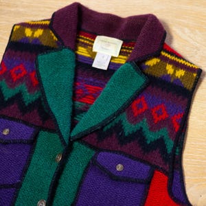 May include: A multi-colored knitted vest with a southwestern pattern. The vest has a collar, buttons, and two pockets. The vest is made of wool and has a soft, comfortable feel.