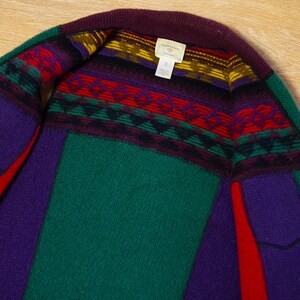 May include: A green, purple, and red striped cardigan with a geometric pattern around the neckline. The label reads "Lauren Ralph Lauren,  Cardigan".