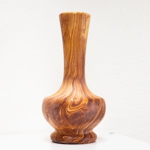 May include: A wooden vase with a brown and orange swirl pattern. The vase has a narrow neck and a wide base.
