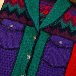 May include: A multi-colored knitted vest with a southwestern pattern. The vest has a collar, two pockets, and a button closure.