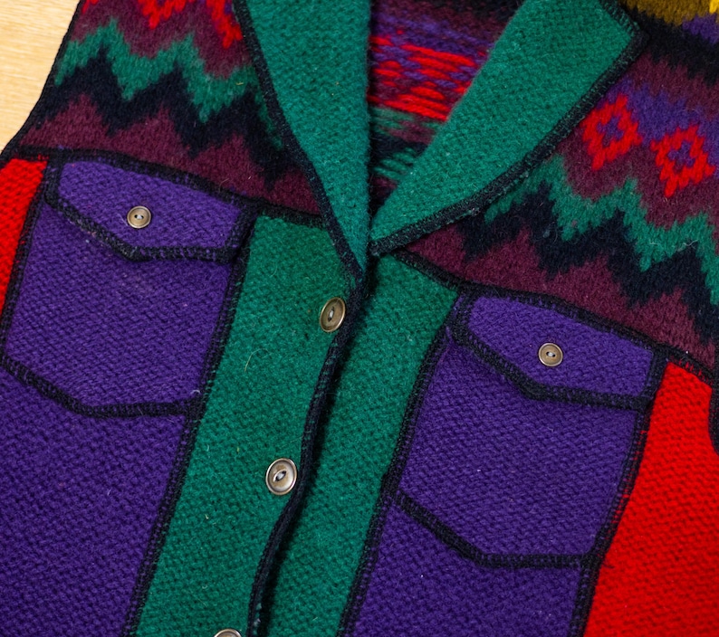 May include: A multi-colored knitted vest with a southwestern pattern. The vest has a collar, two pockets, and a button closure.