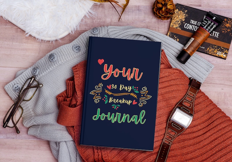 May include: A blue journal with the text "Your 30 Day Breakup Journal" in colourful lettering with a heart and floral design.