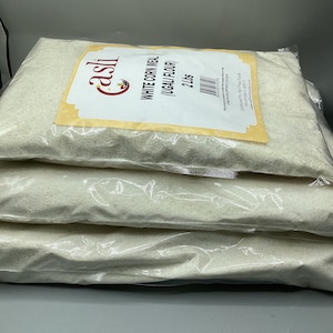 May include: Three transparent bags of white cornmeal, labelled "White Corn Meal (Ugali Flour)", each containing 2 lbs. The bags are stacked, with the top one showing the "casli" logo and product details. The product is a type of flour.