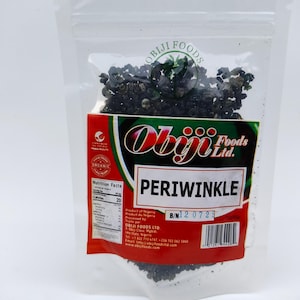May include: A clear plastic bag filled with dark periwinkle. The bag has a red and white label with the text "PERIWINKLE" and "Obiji Foods Ltd.". The label also includes nutritional information and the text "Product of Nigeria".